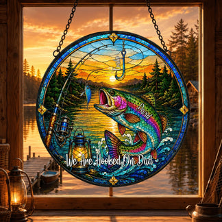 Stained glass panel with fishing theme and sunset over water scene, placed in front of a window.