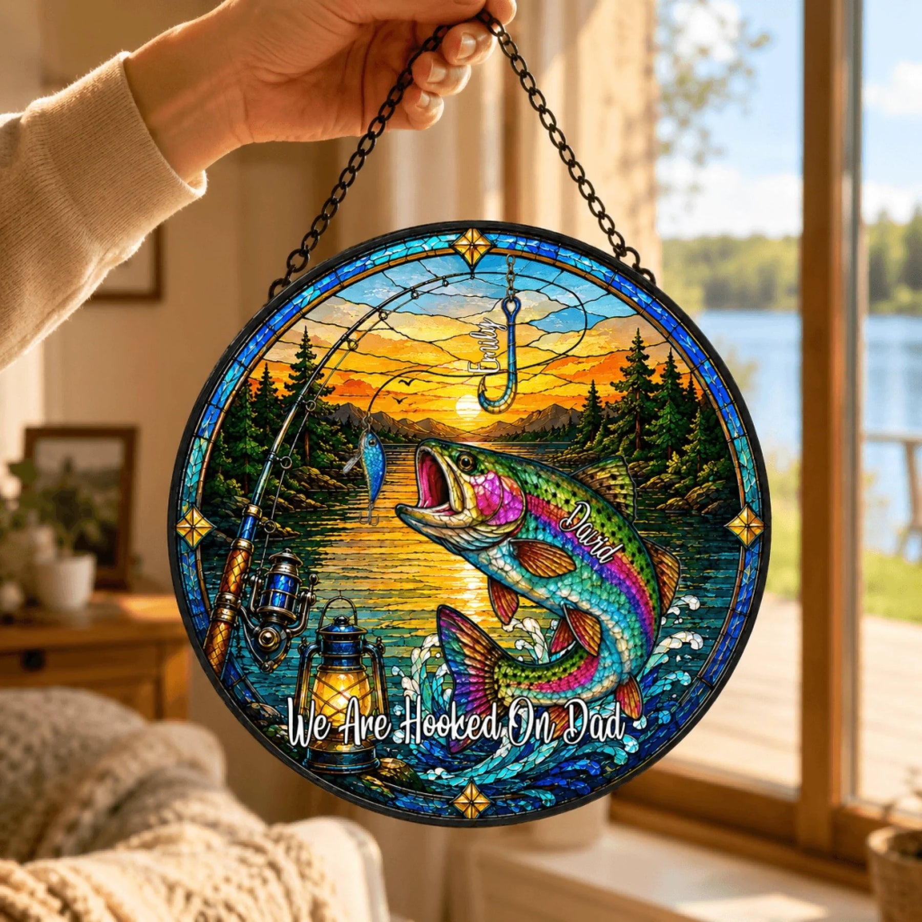 Decorative stained glass panel with fishing theme and sunset over a lake, held by a hand.
