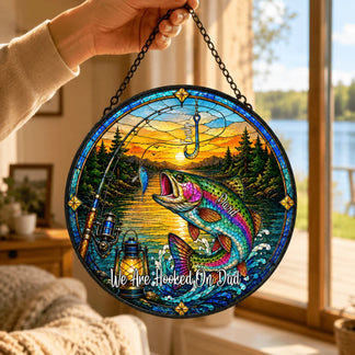 Decorative stained glass panel with fishing theme and sunset over a lake, held by a hand.