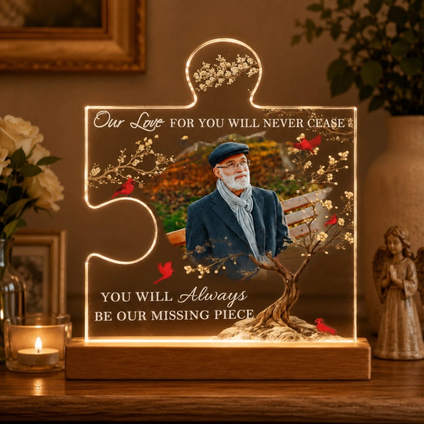 An illuminated acrylic puzzle piece plaque featuring an older man, a tree, and red birds. Text reads 'Our Love FOR YOU WILL NEVER CEASE' and 'YOU WILL Always BE OUR MISSING PIECE'.