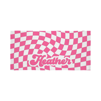 A personalized pink and white wavy checkerboard beach towel with the name Heather written in a groovy retro font.
