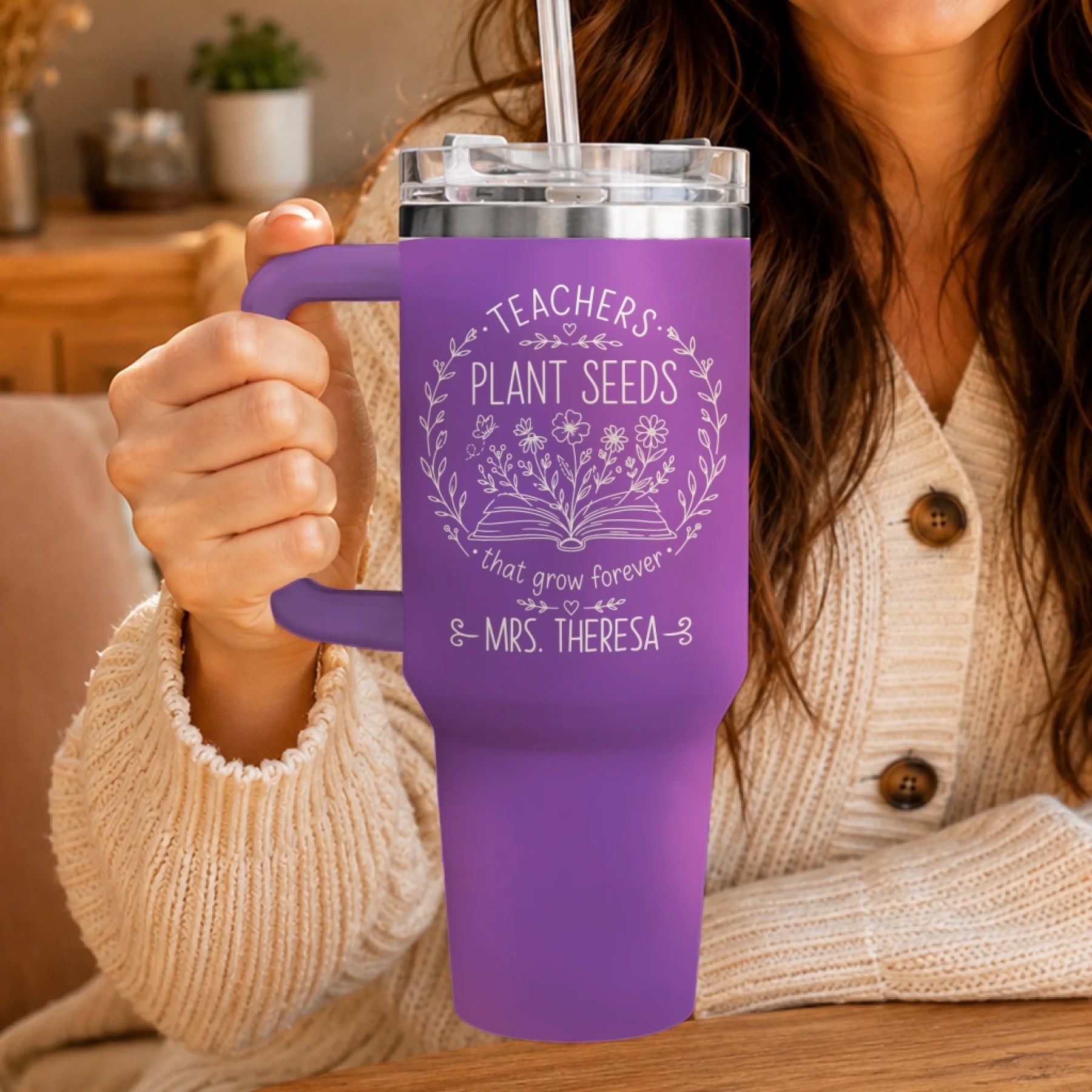 Close-up of a person holding a purple personalized teacher tumbler with 'Teachers Plant Seeds' design.