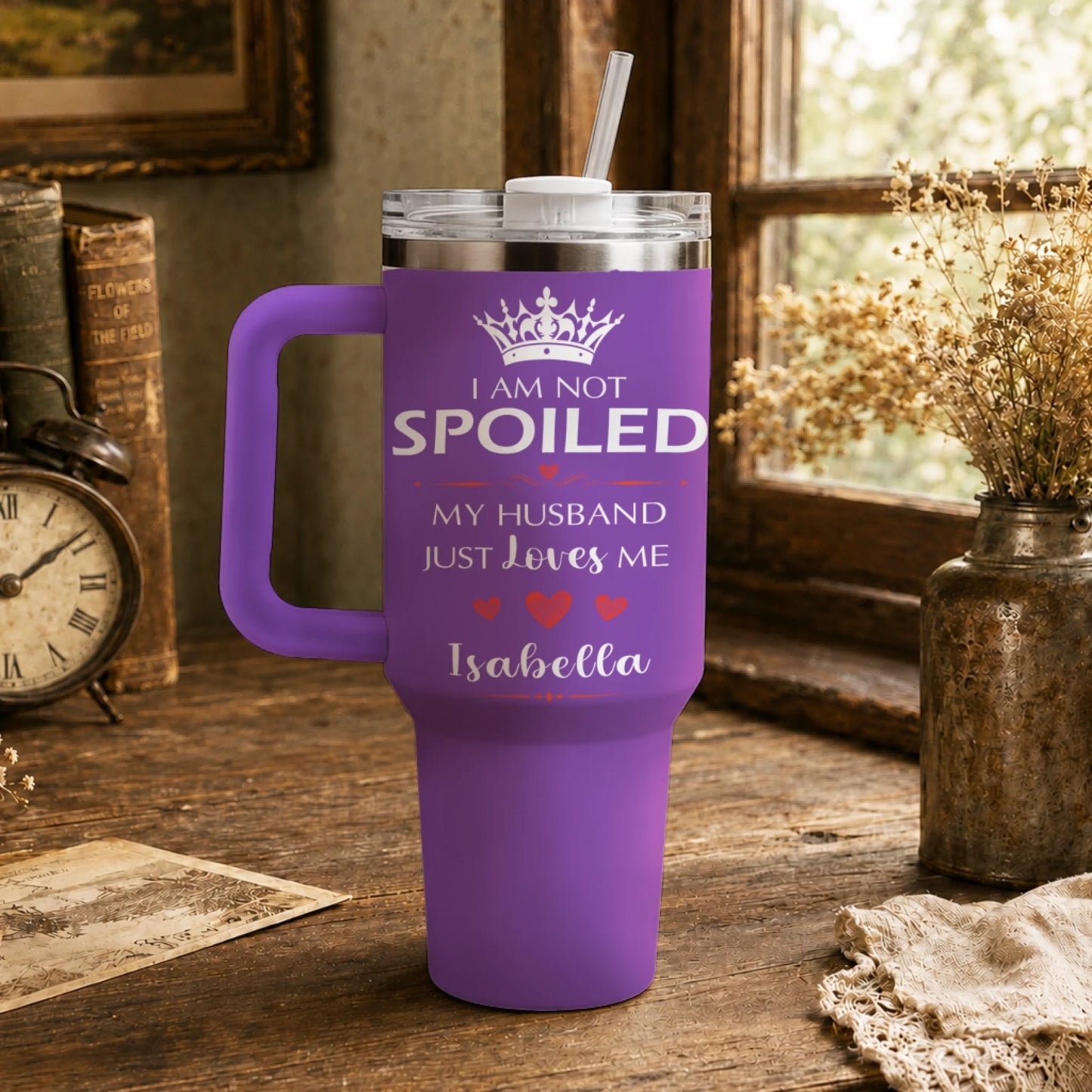 A purple travel tumbler with handle and straw sitting on a vintage wooden desk.