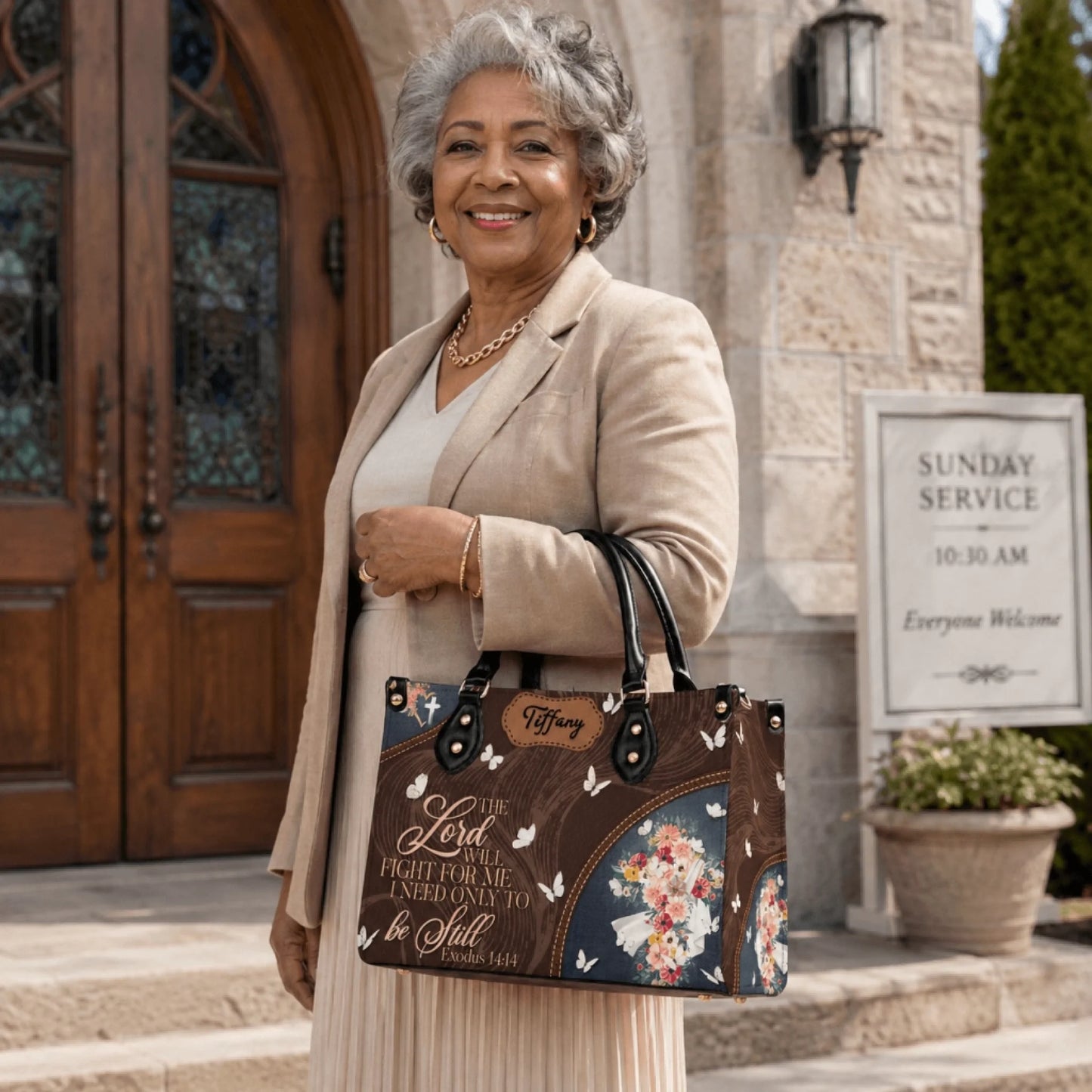 A senior woman holding a custom faith themed handbag with Exodus 14:14 verse outside a church sunday service.