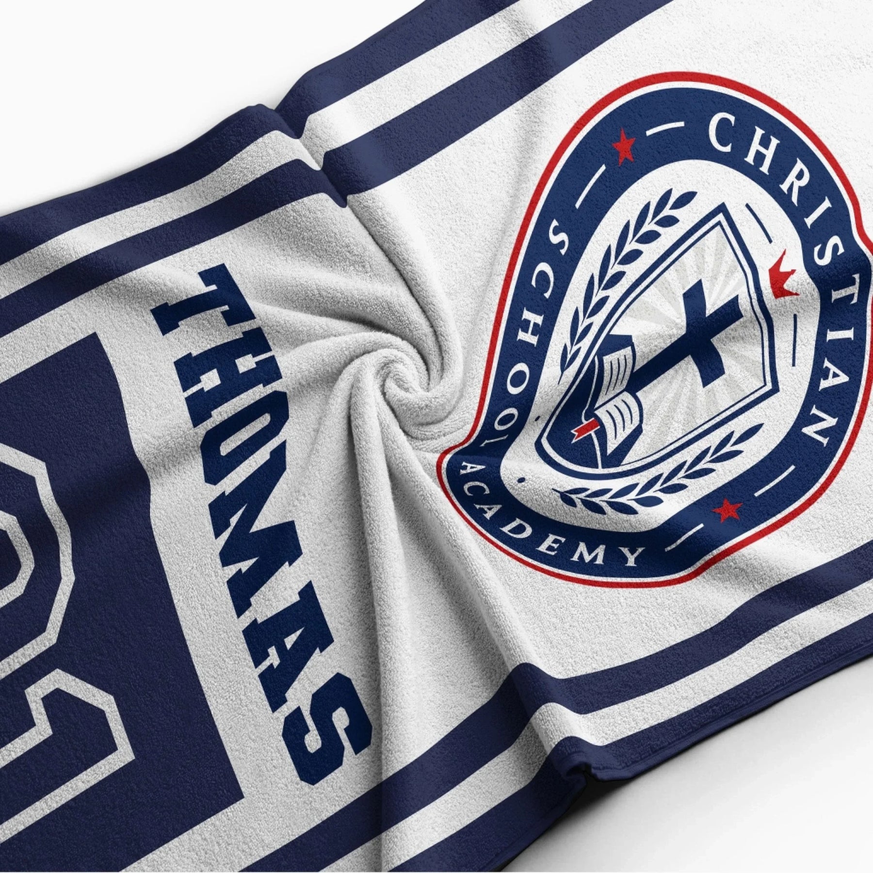 Close up of a soft personalized beach towel showing the Christian School Academy logo and the custom name Thomas.