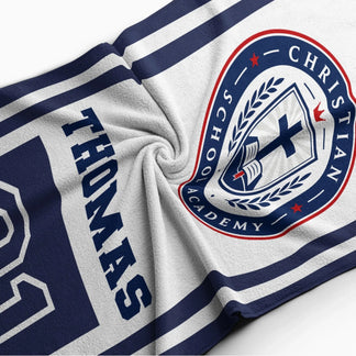 Close up of a soft personalized beach towel showing the Christian School Academy logo and the custom name Thomas.