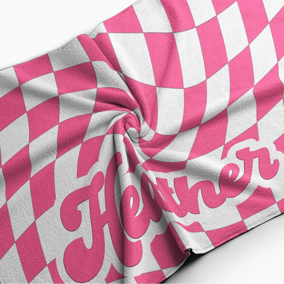 Close up of a plush pink and white wavy checkerboard beach towel with the custom name Heather in retro lettering.
