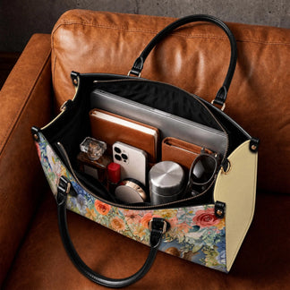 Interior view of a floral handbag filled with daily essentials like a laptop, phone, perfume, and water bottle.