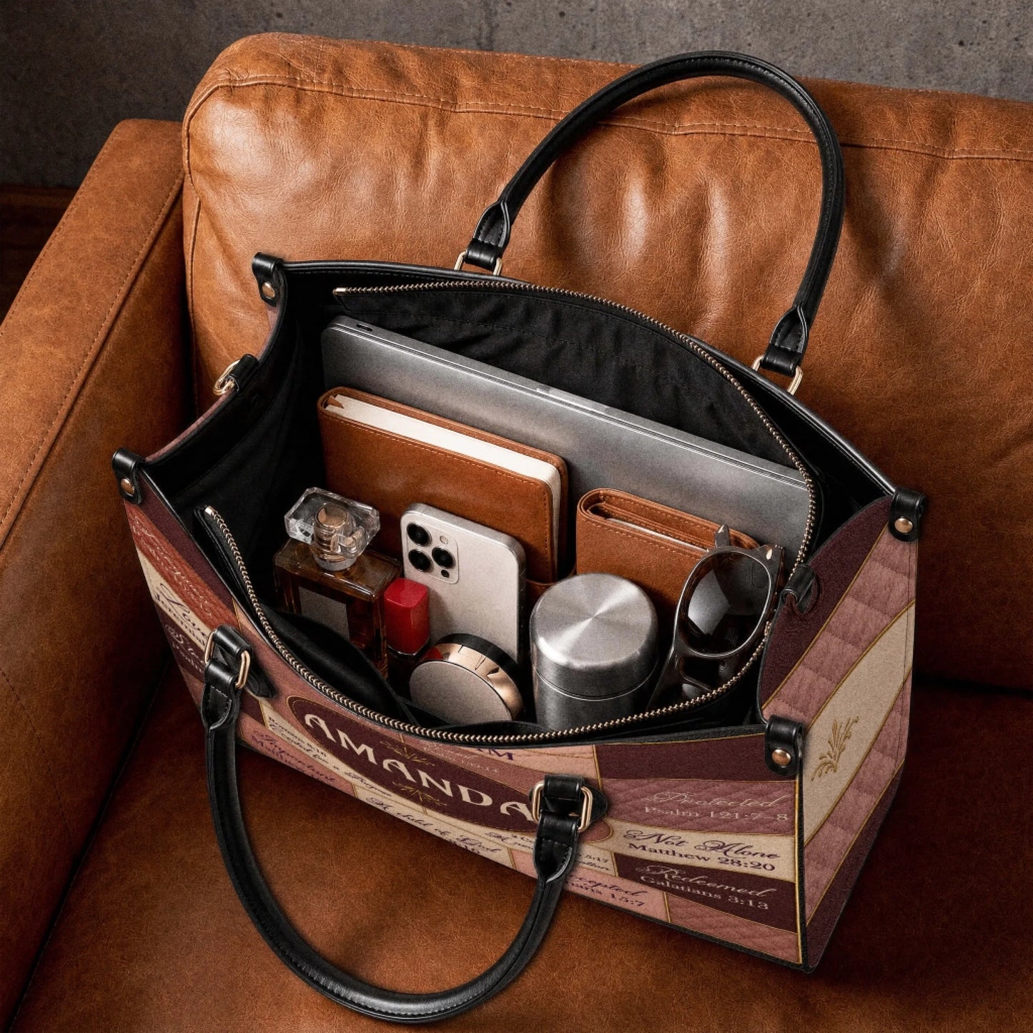 The spacious interior of a custom Amanda religious handbag filled with everyday items like a laptop, journal, and phone.