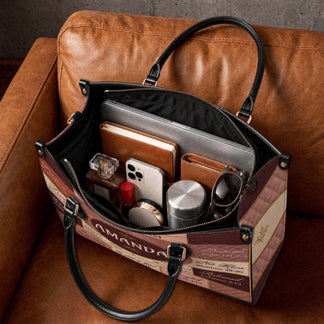 The spacious interior of a custom Amanda religious handbag filled with everyday items like a laptop, journal, and phone.