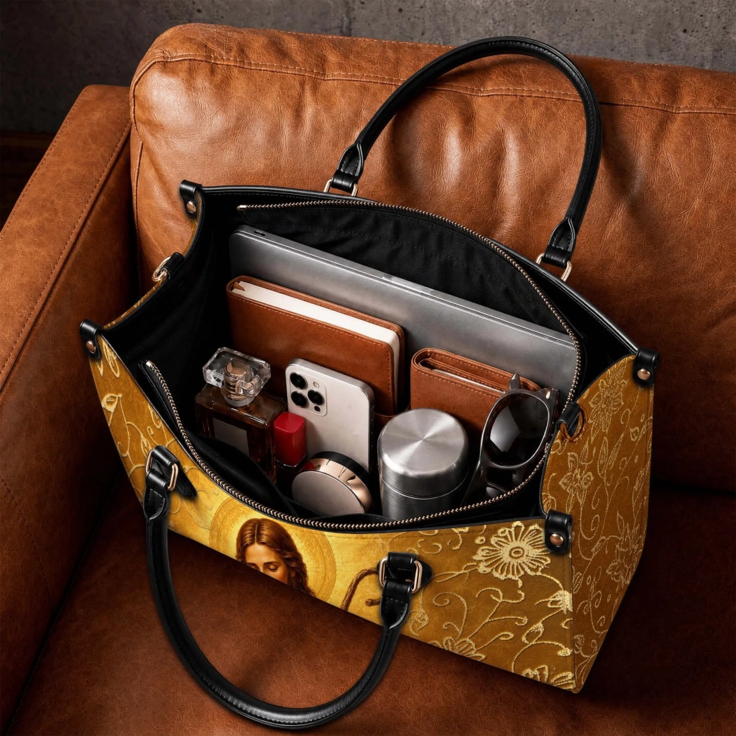 Spacious interior of a personalized Jesus handbag, filled with daily essentials like a laptop, notebook, and phone.