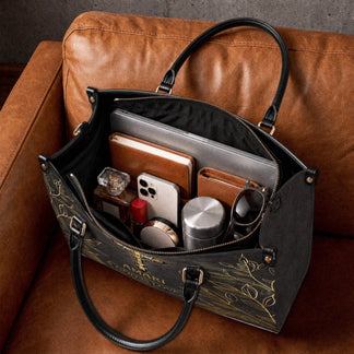 Black leather tote bag filled with everyday items like a laptop wallet phone and makeup for stylish faith living