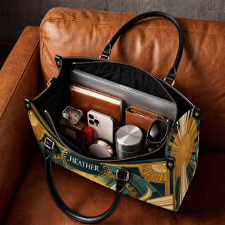 Interior view of a personalized Christian tote bag filled with a laptop, notebook, and personal items on a leather chair.