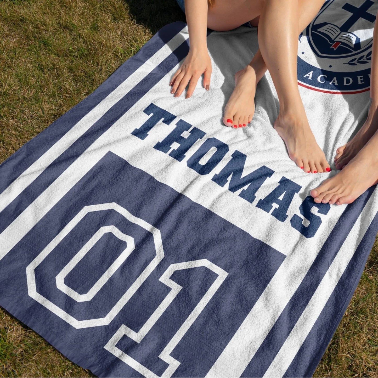 A student beach towel with the Christian School Academy emblem, customized with the name Thomas and number 01.