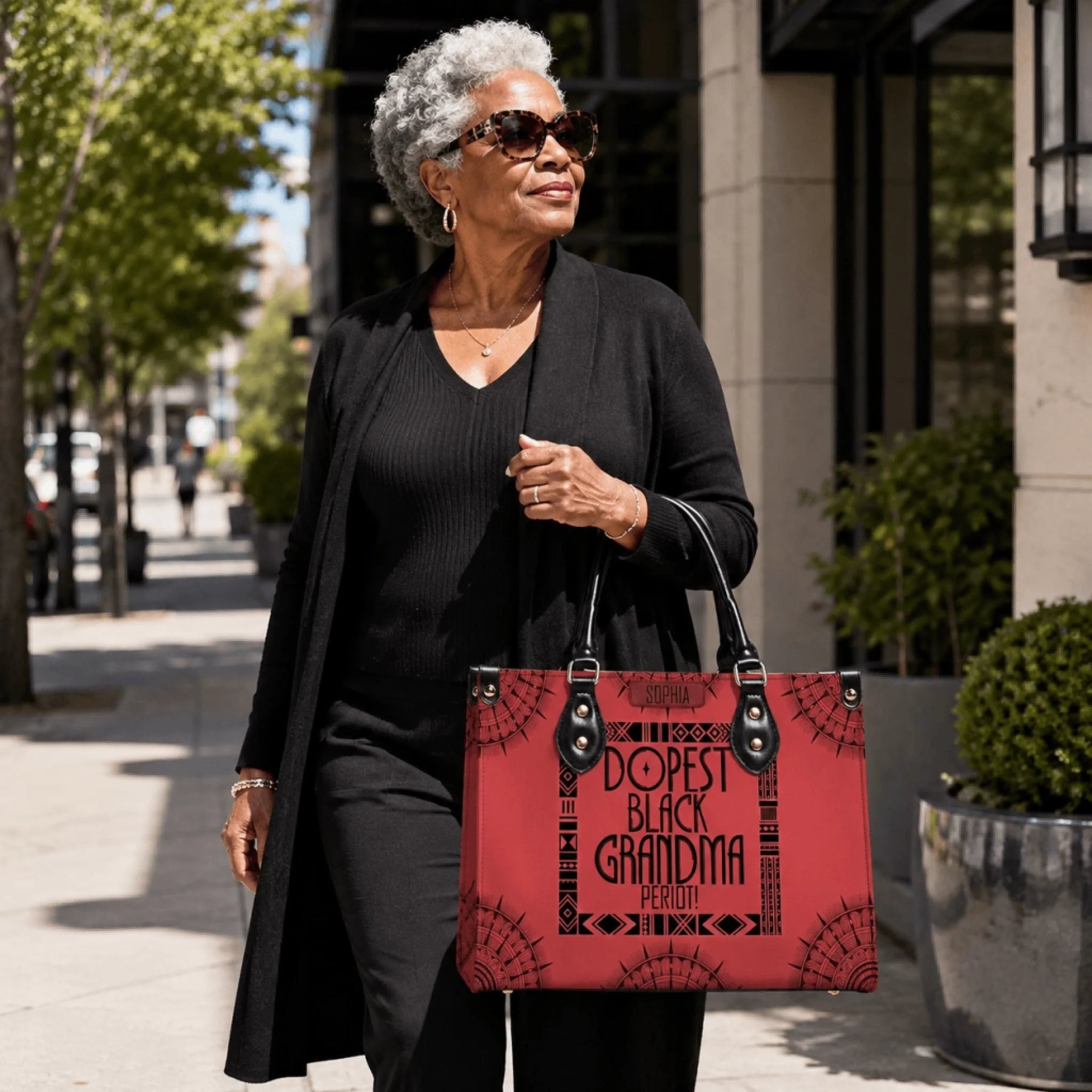 Elderly woman carrying a red personalized handbag with the text Dopest Black Grandma Period and the name Sophia.