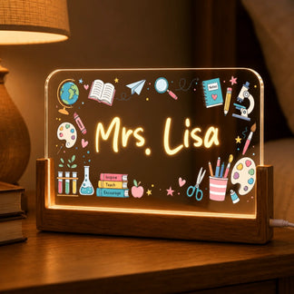An illuminated rectangular acrylic sign with a wooden base, featuring colorful teacher-themed doodles and the glowing name 'Mrs. Lisa.'