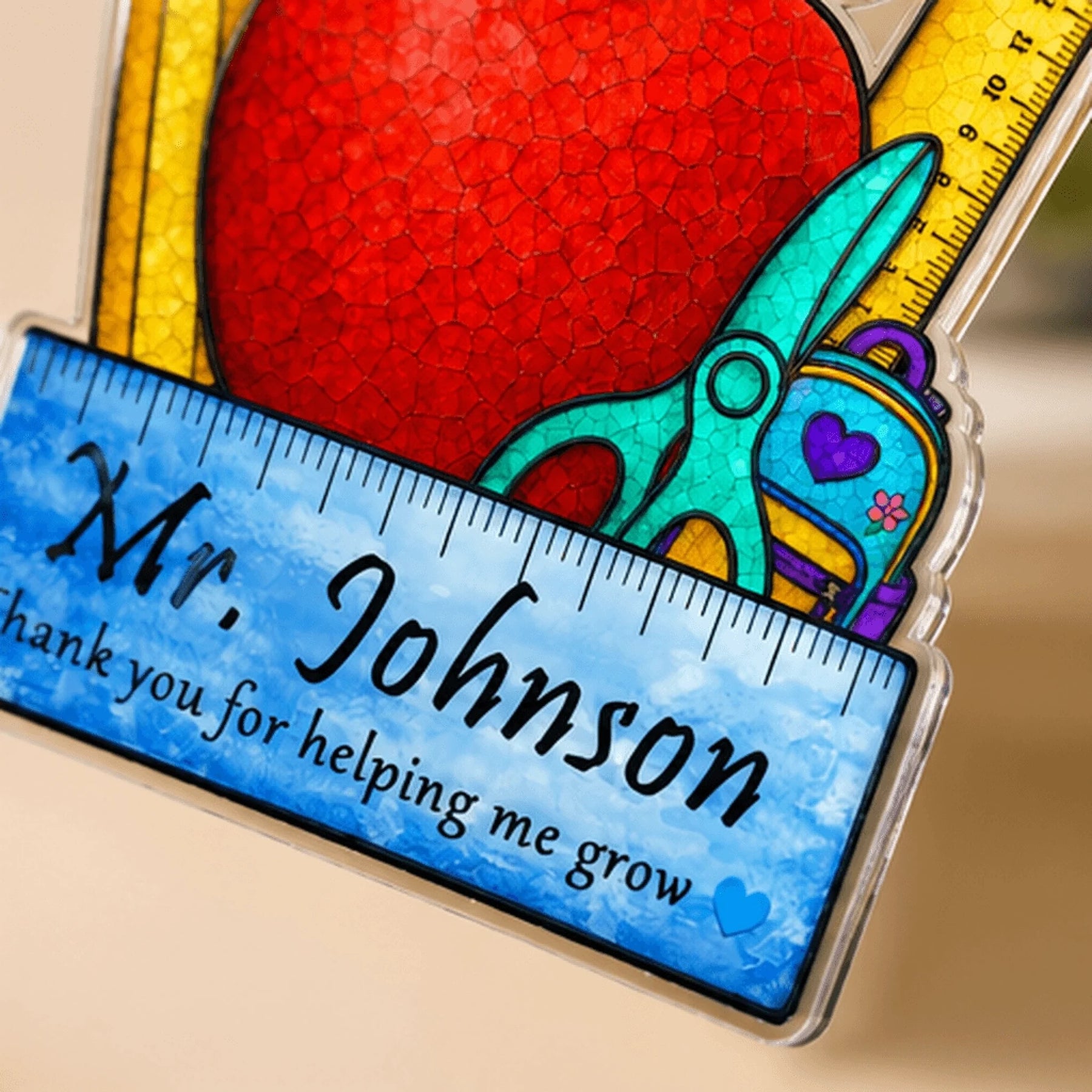 Close-up of personalized suncatcher with teacher name and colorful school supplies