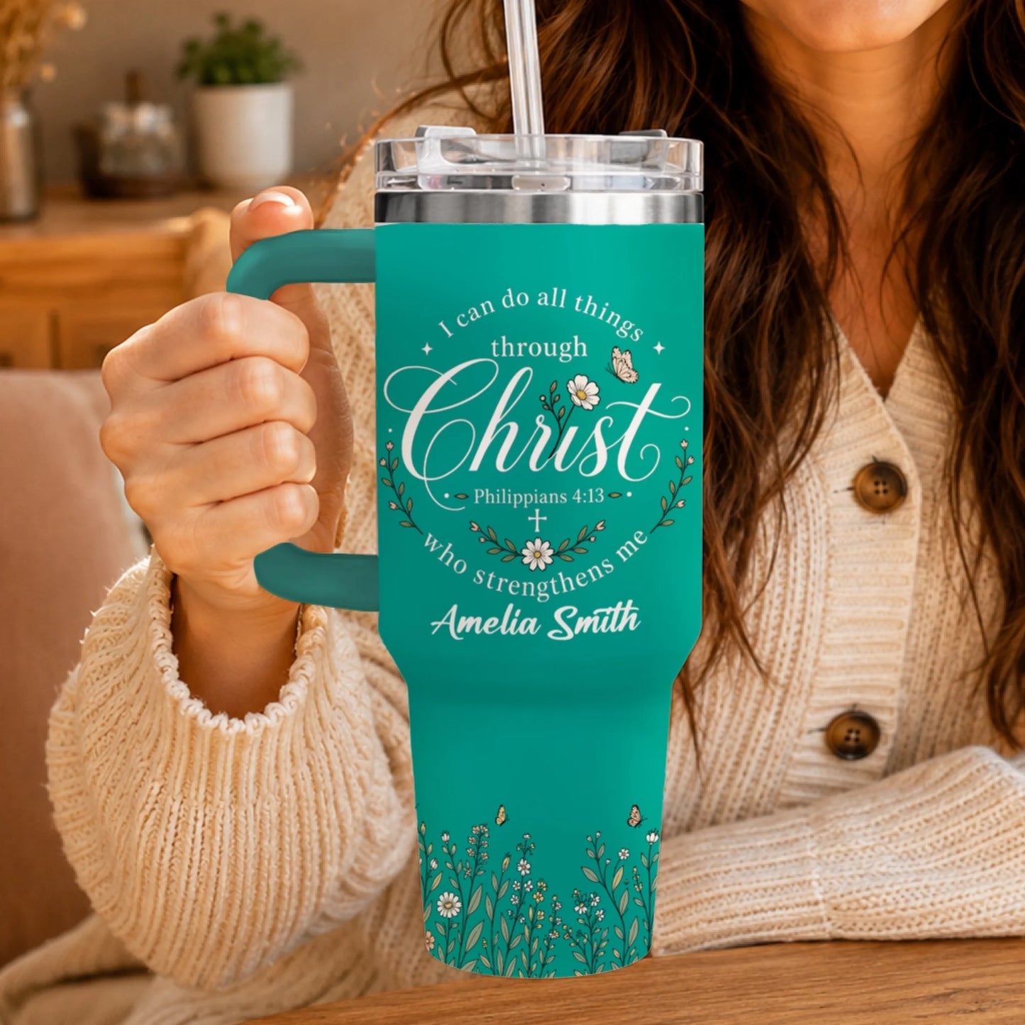 Teal stainless steel tumbler held by a person, featuring religious scripture, floral accents, and a personalized name.
