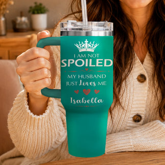 A person holding a teal travel tumbler featuring personalized I am not spoiled text.