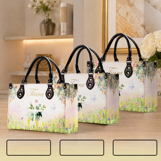Three sizes of personalized floral cross tote bags with butterflies and custom names displayed on a wooden surface.