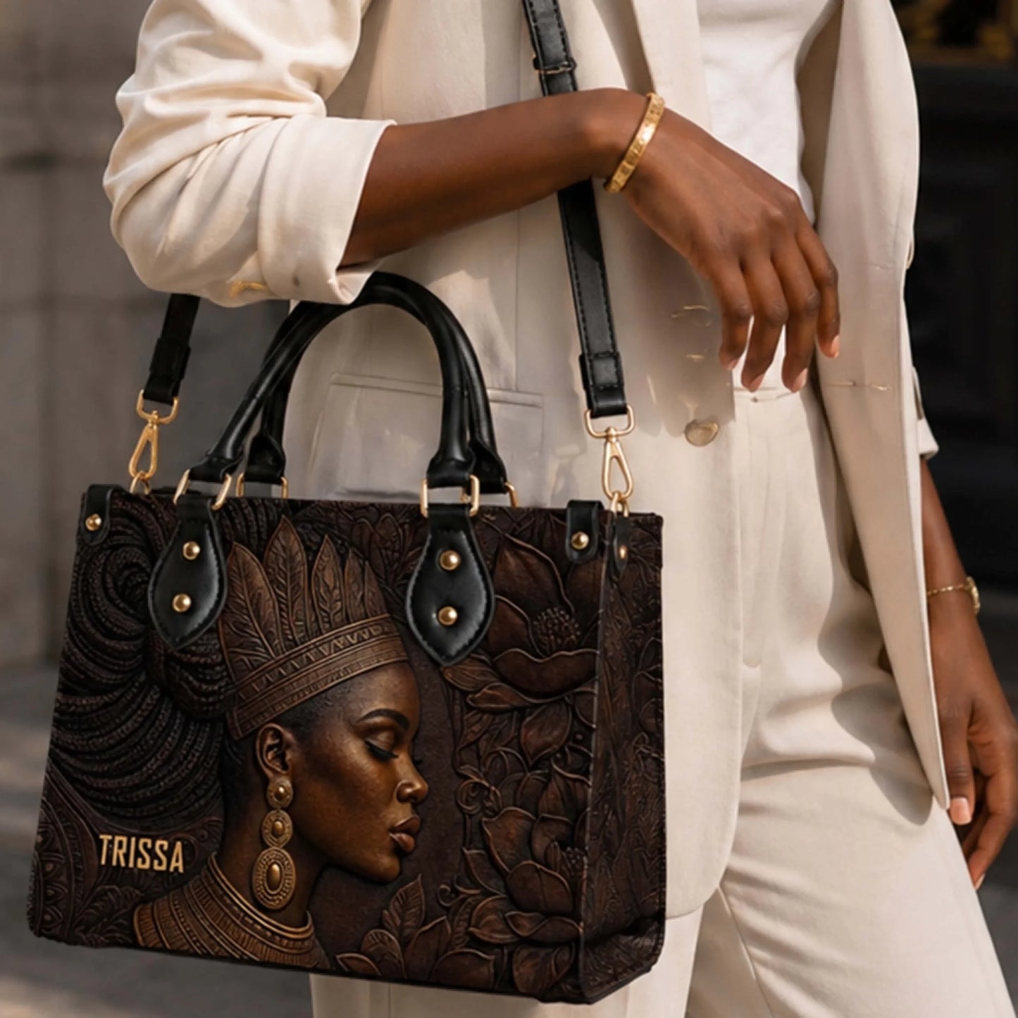 A woman carrying a stylish Trissa shoulder bag with an embossed African American woman portrait and black handle.