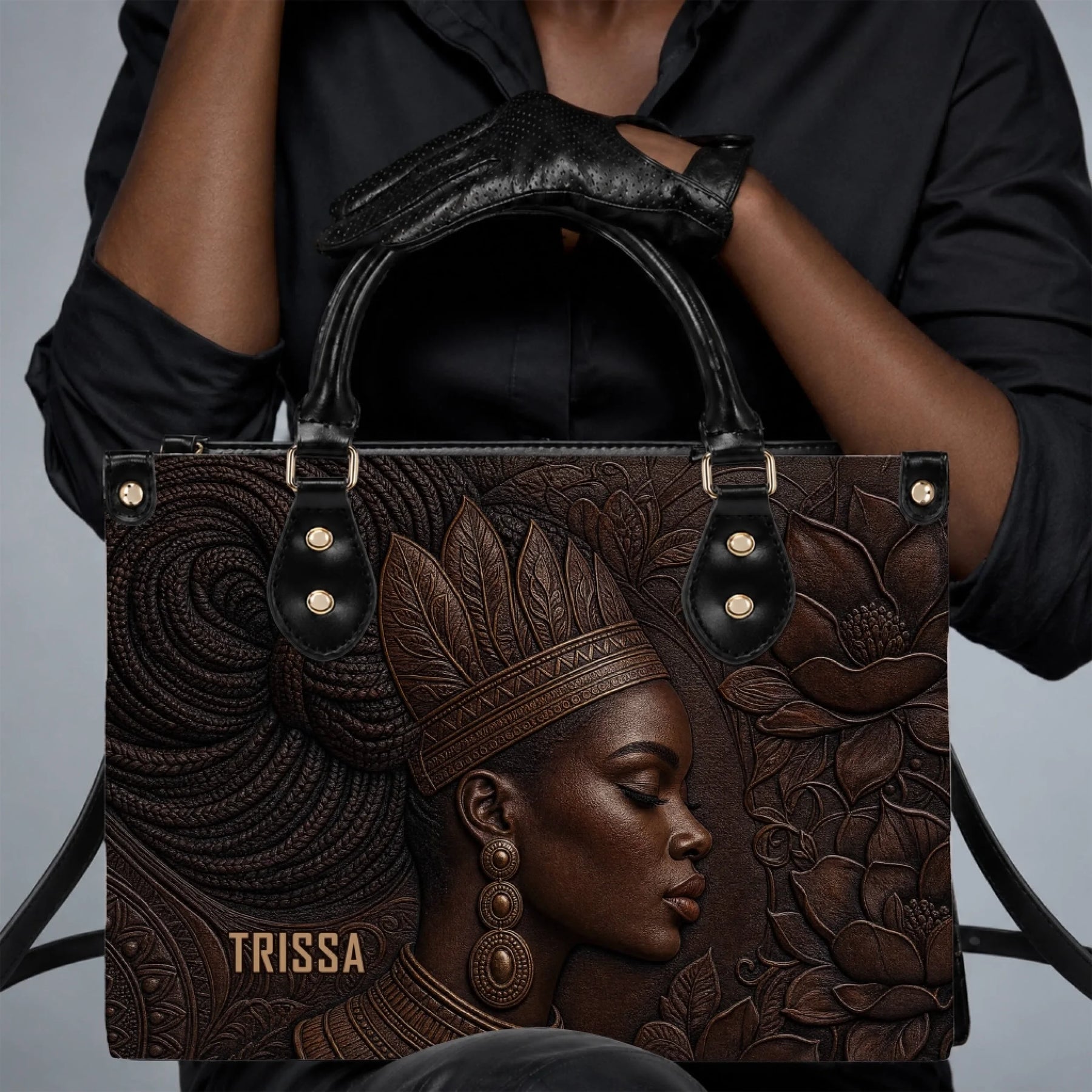 Close up of an elegant black and brown leather tote bag showcasing an embossed portrait of a woman in accessories.