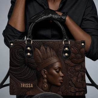 Close up of an elegant black and brown leather tote bag showcasing an embossed portrait of a woman in accessories.