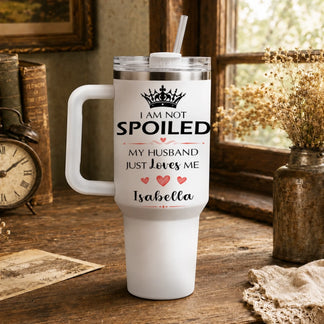 A white travel tumbler with crown and hearts design sitting on a rustic wooden desk.