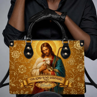 A woman wearing a black outfit holding a personalized Christian handbag featuring a gold floral design and Psalm 23.