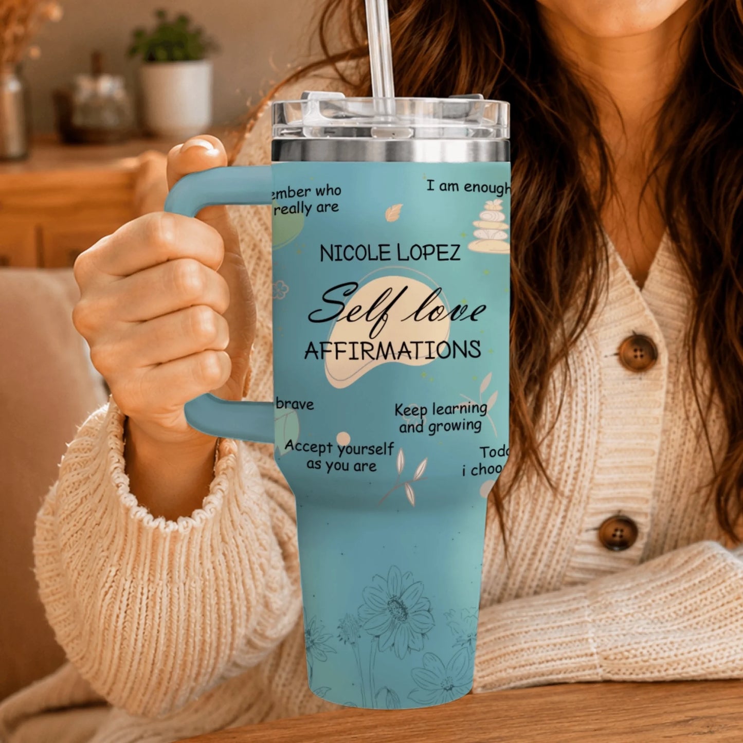A woman holding a blue stainless steel tumbler with custom affirmations and floral graphics.