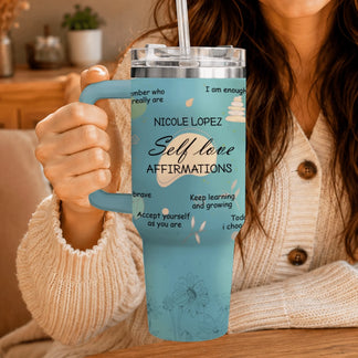 A woman holding a blue stainless steel tumbler with custom affirmations and floral graphics.
