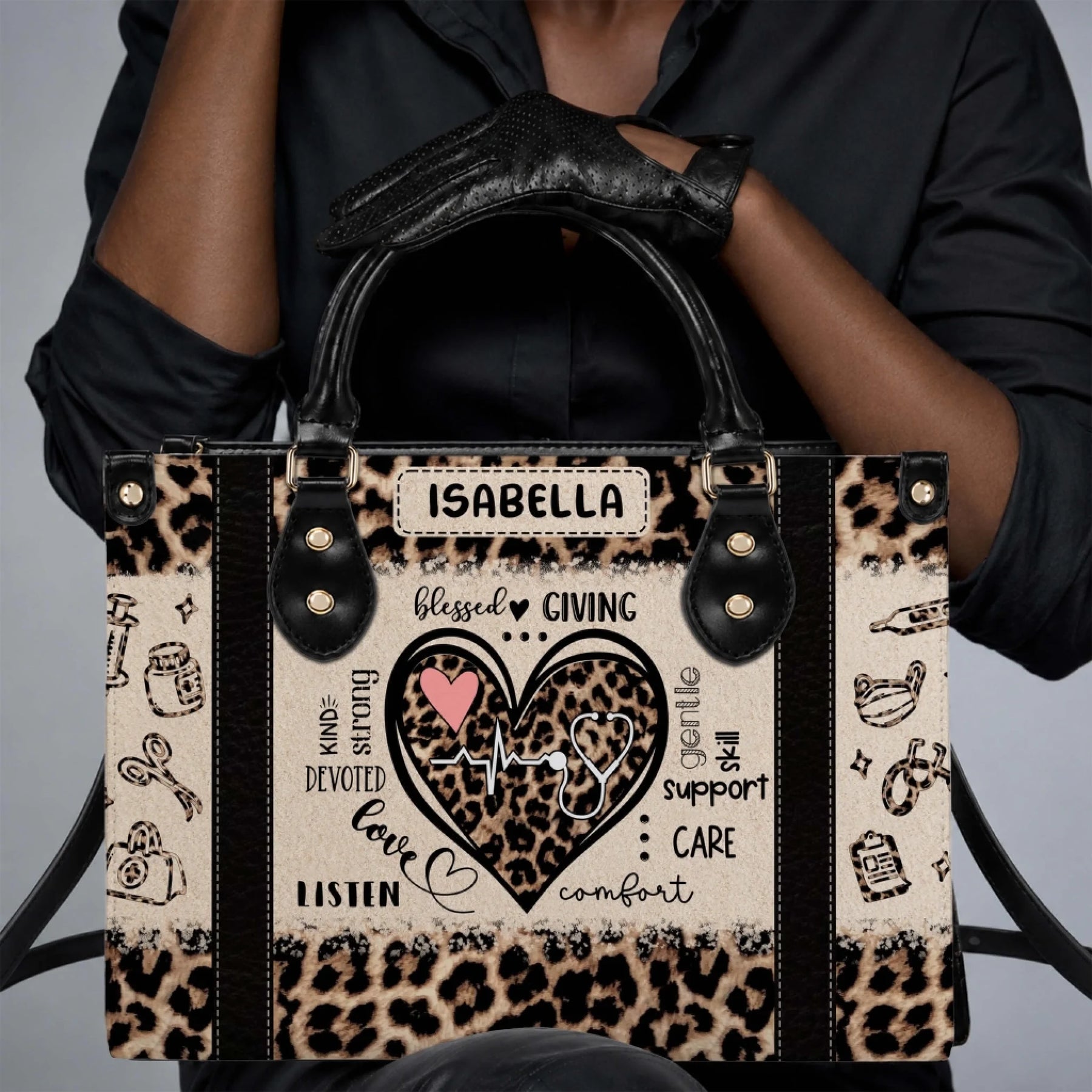 Close up of a person holding a custom leopard print nurse tote bag with stethoscope heartbeat motif and Isabella name personalization.