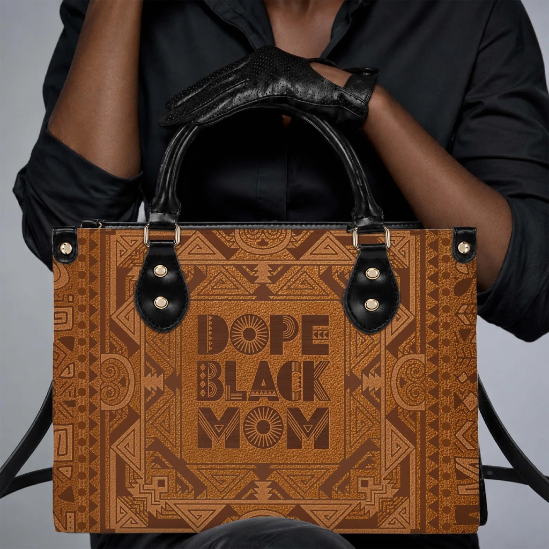 A person wearing black gloves holds a stylish brown patterned handbag with the text Dope Black Mom prominently.