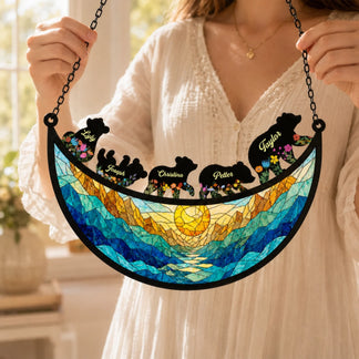 A woman holding a personalized family bear suncatcher gift with a beautiful mountain sun design and custom names.