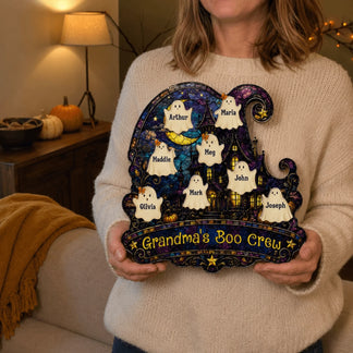 A woman holding a custom Grandma's Boo Crew acrylic wall hanging decorated with cute ghosts and family names.