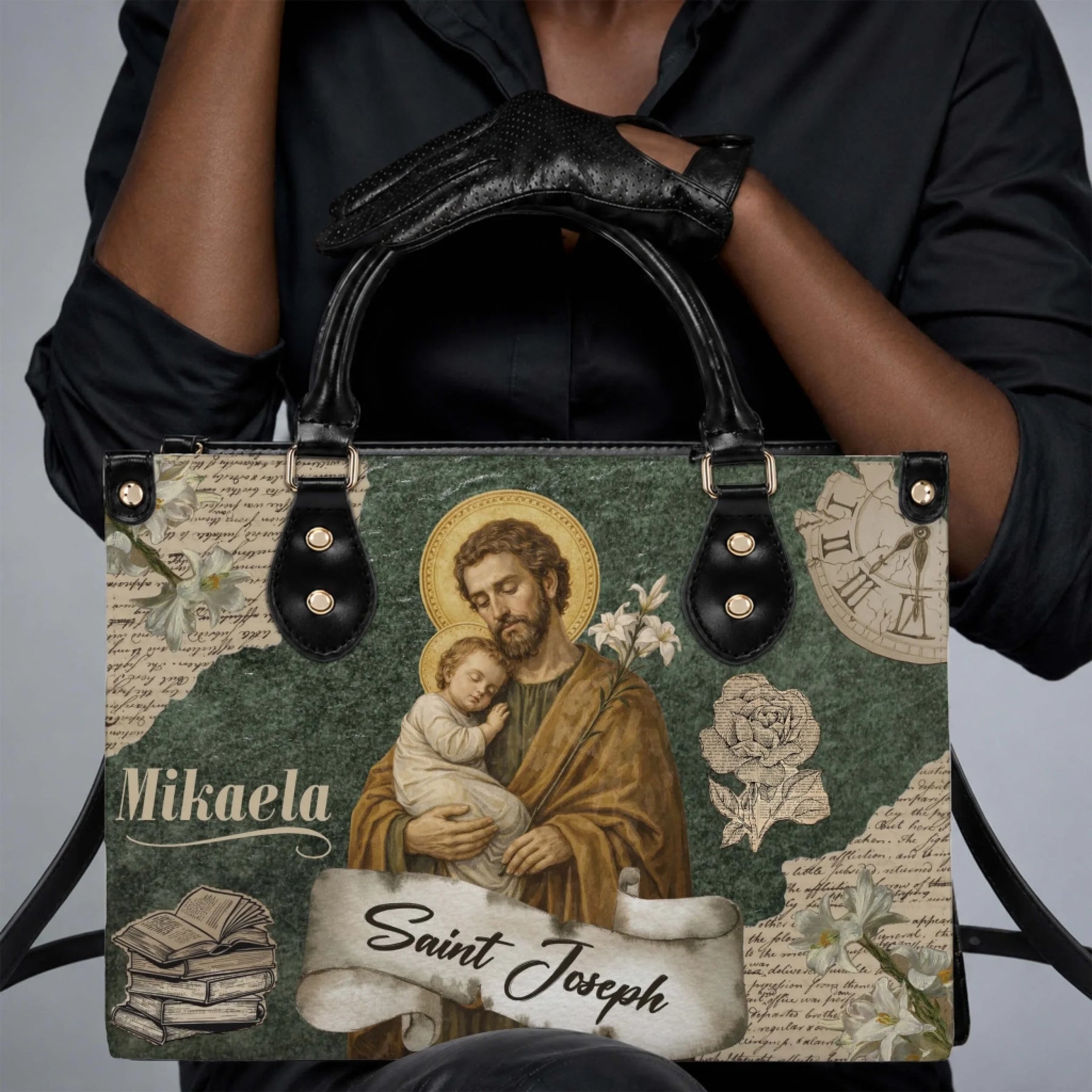 A woman holding a custom Mikaela Saint Joseph religious print handbag with black leather handles and trim.
