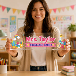 A smiling teacher holding a custom acrylic desk plaque with colorful kindergarten school theme graphics.