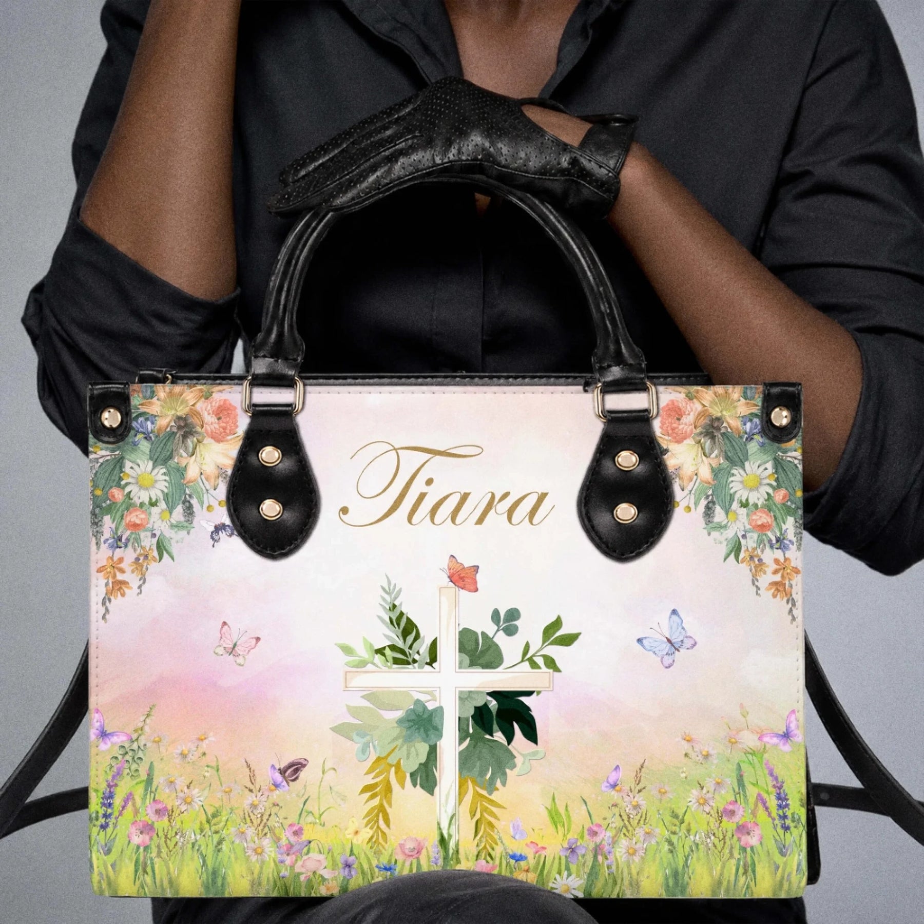 Close up of a person holding a custom-printed handbag with a floral cross and the name Tiara on a soft spring-themed background.