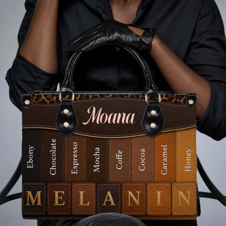 Close up of a woman wearing black gloves holding a personalized melanin-themed handbag with varied skin tone shades.
