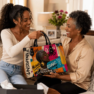 Young woman gifting a stylish, art-inspired shoulder bag to an older woman in a warm indoor setting.